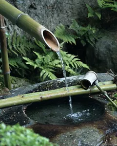 A small stream of water flows from a bamboo fountain
