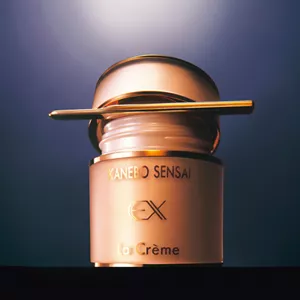 A cream jar opened with a spatula between a glass jar and lid