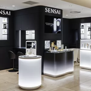 A shot of the SENSAI shop counter with white round tables and a black wall